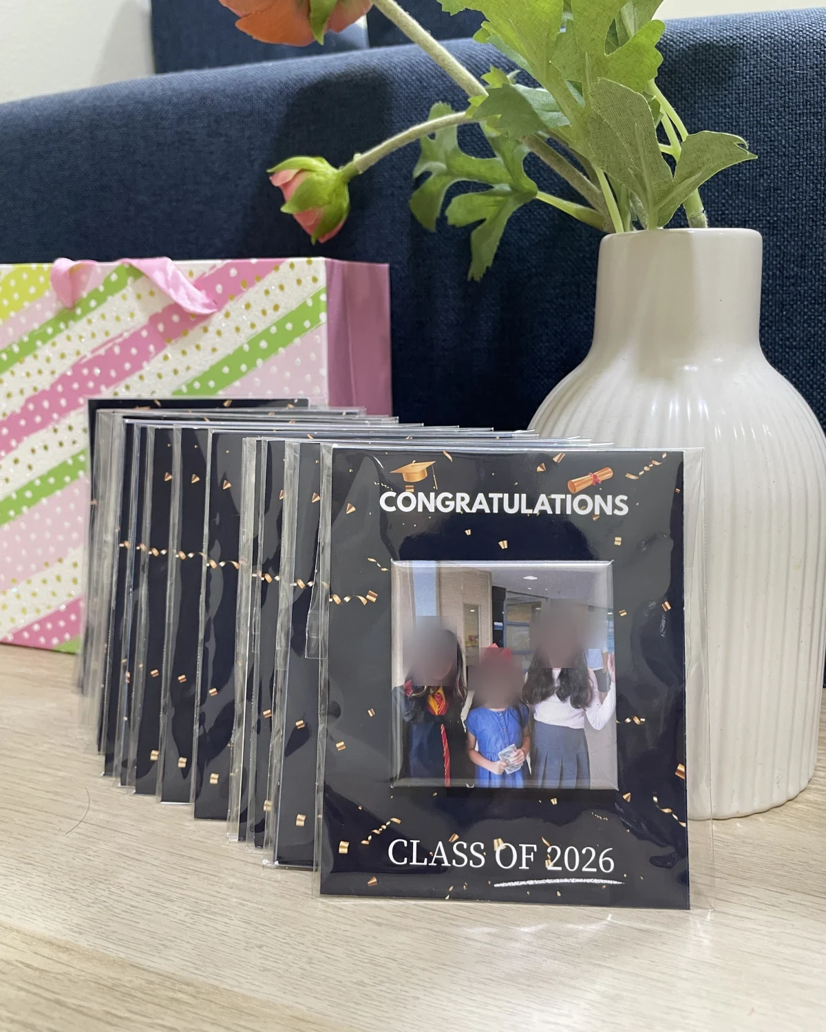 A stack of “Congratulations, Class of 2026” cards, each holding a photo magnet