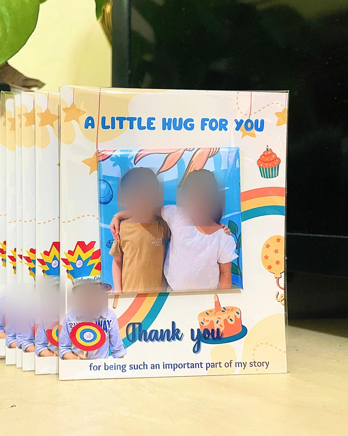 A row of birthday return-gift cards reading “A little hug for you”, each holding a photo magnet