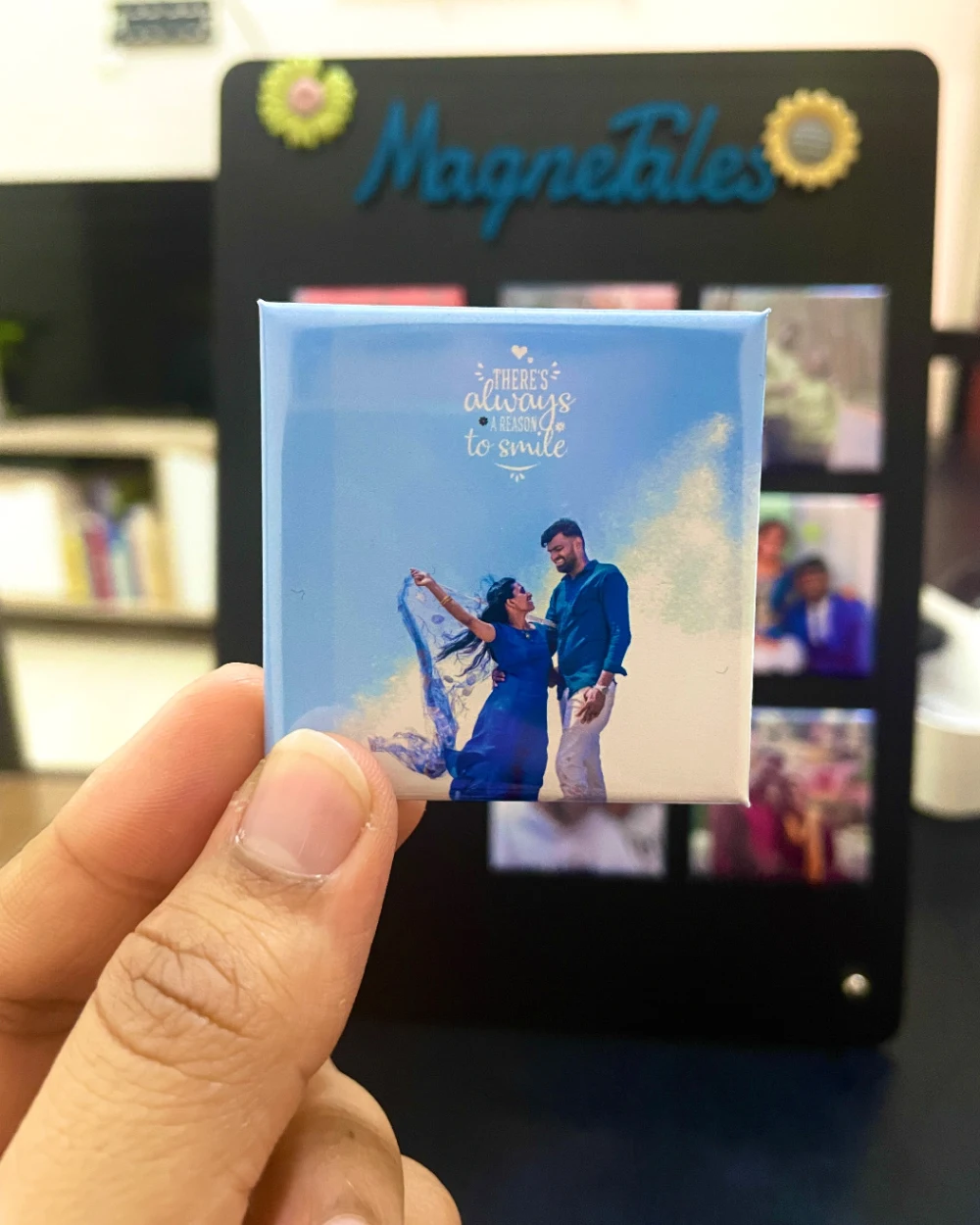 A classic 3D magnet of a couple on a beach, held up in front of a MagneTales board